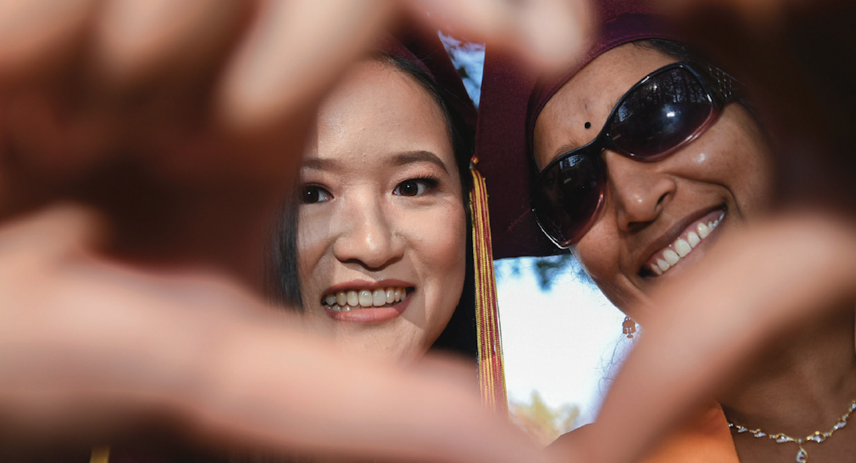 two young women making a heart with fingers