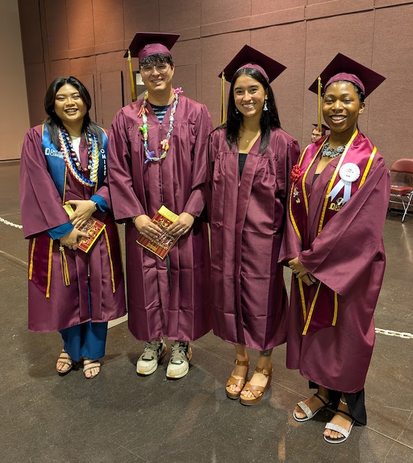 four grads smiling and standing in row