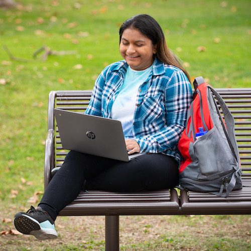 young woman sitting outside with laptop computer